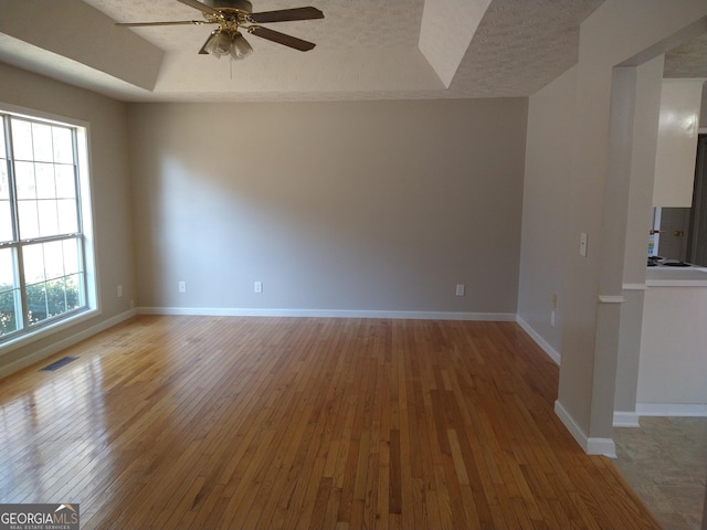 unfurnished room featuring light wood-type flooring, baseboards, and a tray ceiling