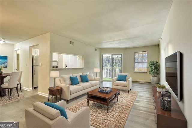 living room with wood finished floors, visible vents, and baseboards