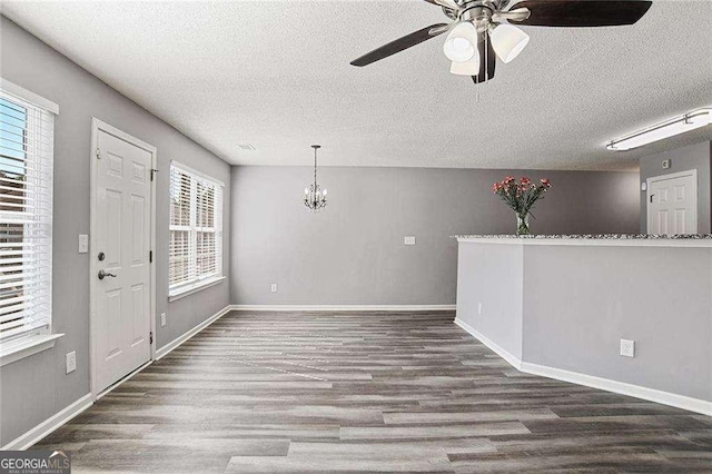 entryway featuring a textured ceiling, ceiling fan with notable chandelier, wood finished floors, and baseboards