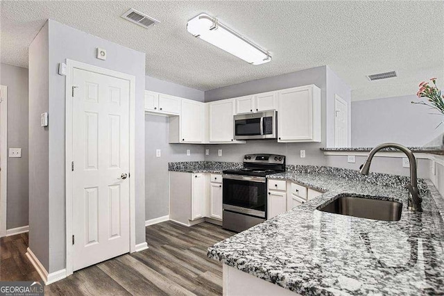 kitchen with stainless steel appliances, a sink, visible vents, and light stone countertops