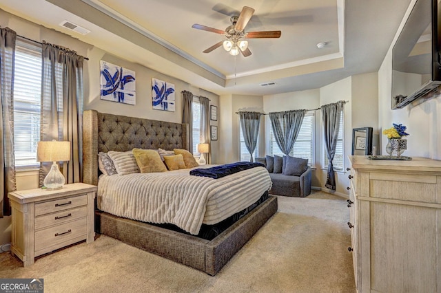 bedroom with light carpet, multiple windows, a raised ceiling, and visible vents