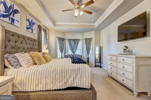 bedroom featuring light carpet, baseboards, a tray ceiling, and a ceiling fan