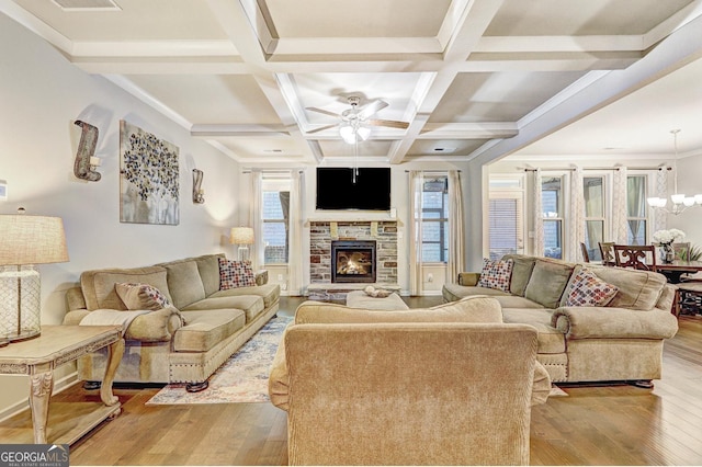 living area with a stone fireplace, coffered ceiling, wood finished floors, and beam ceiling