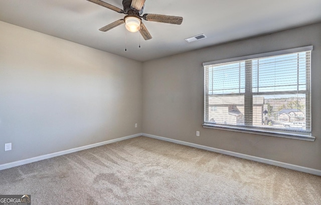 carpeted empty room featuring a ceiling fan, visible vents, and baseboards