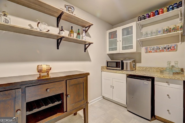 kitchen with open shelves, white cabinets, stainless steel appliances, and light stone counters