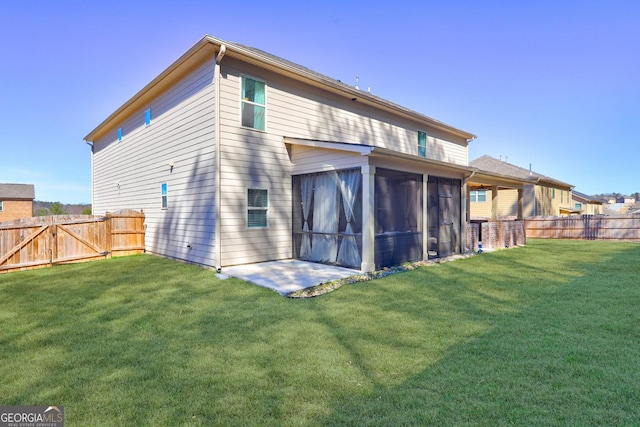 rear view of house featuring a lawn, a fenced backyard, and a sunroom