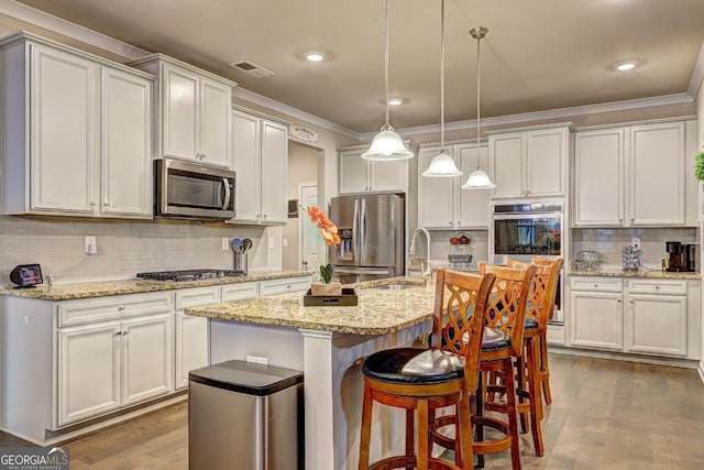 kitchen featuring visible vents, dark wood finished floors, appliances with stainless steel finishes, ornamental molding, and a sink