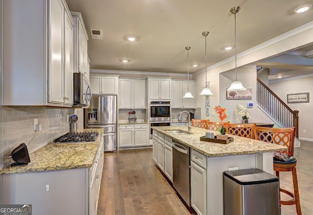 kitchen with dark wood-style floors, a breakfast bar, appliances with stainless steel finishes, ornamental molding, and a sink