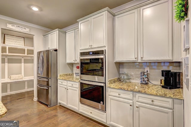 kitchen featuring crown molding, stainless steel appliances, tasteful backsplash, wood finished floors, and light stone countertops