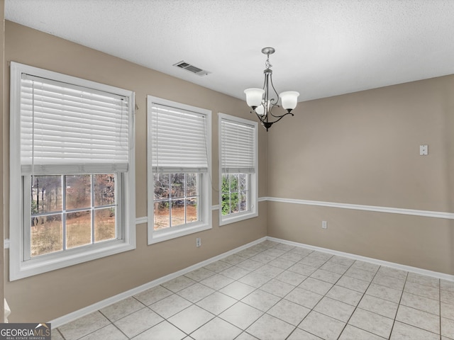 unfurnished room featuring a chandelier, a textured ceiling, visible vents, and baseboards