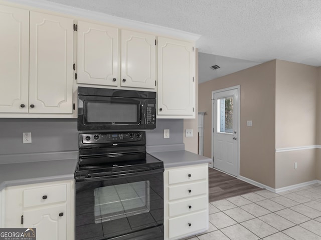 kitchen with a textured ceiling, black appliances, visible vents, and white cabinetry