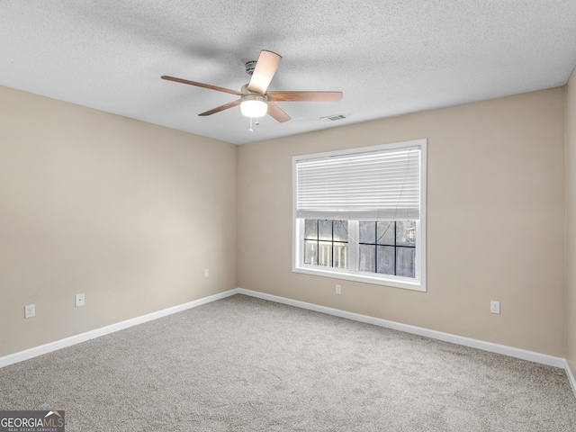 carpeted spare room with ceiling fan, a textured ceiling, visible vents, and baseboards