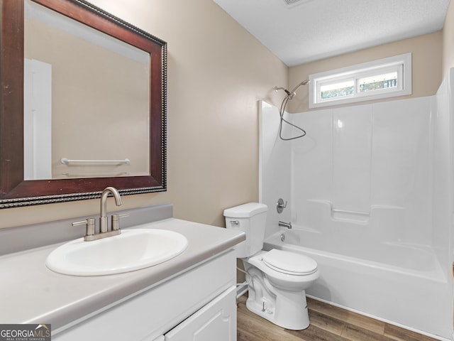 bathroom with a textured ceiling, toilet, wood finished floors, vanity, and tub / shower combination