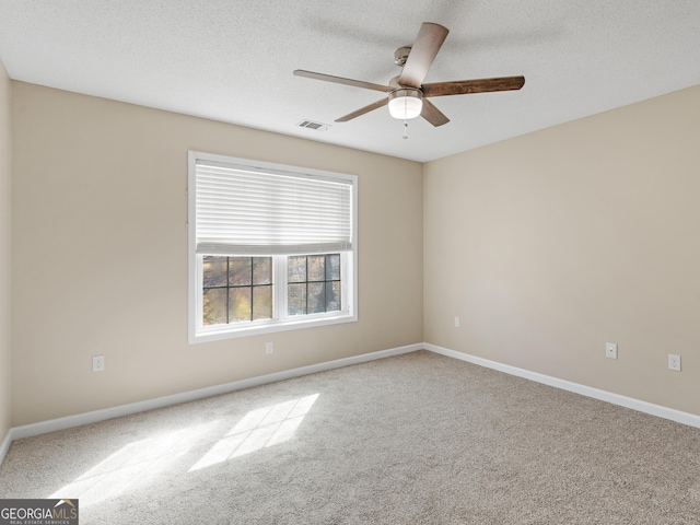 carpeted empty room featuring a textured ceiling, ceiling fan, visible vents, and baseboards