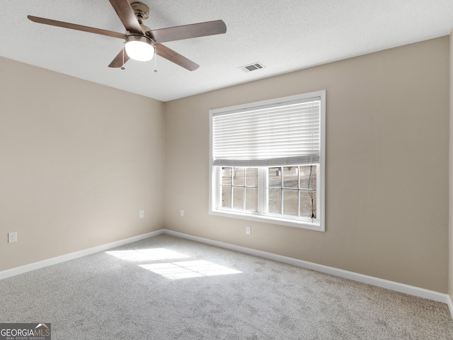 carpeted empty room with a textured ceiling, a ceiling fan, visible vents, and baseboards