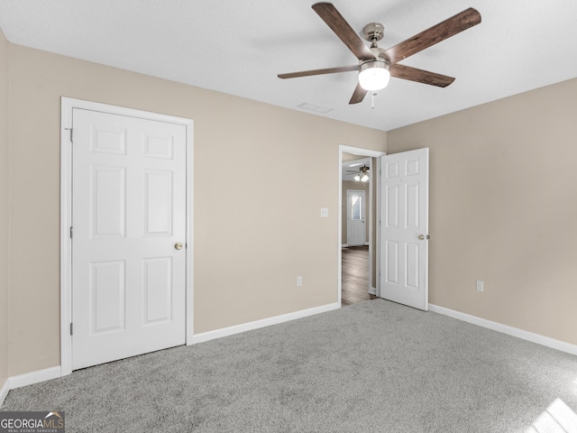 unfurnished bedroom with a ceiling fan, carpet, visible vents, and baseboards