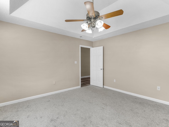 carpeted spare room featuring ceiling fan and baseboards