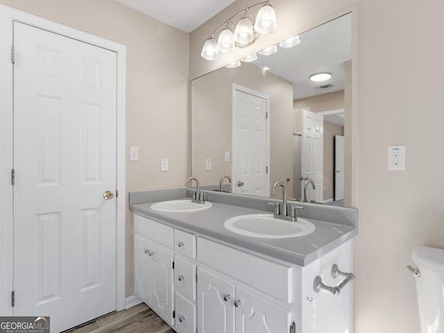 full bath with double vanity, wood finished floors, a sink, and visible vents