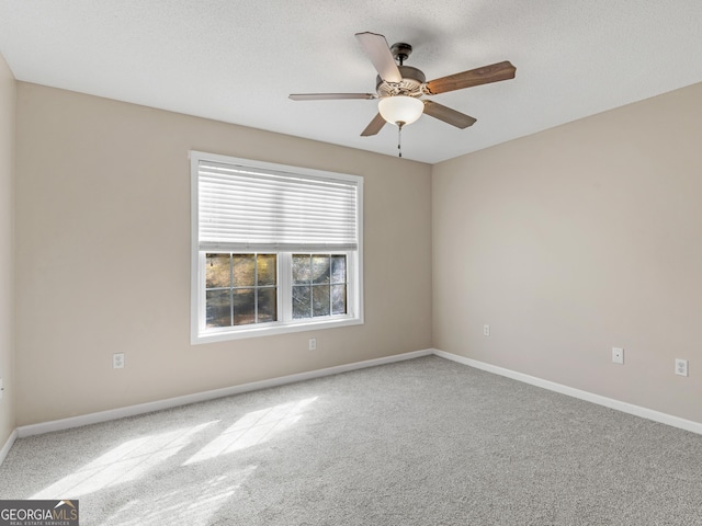 carpeted spare room featuring a ceiling fan, a textured ceiling, and baseboards