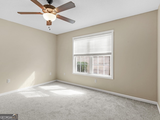 unfurnished room with carpet floors, ceiling fan, baseboards, and a textured ceiling