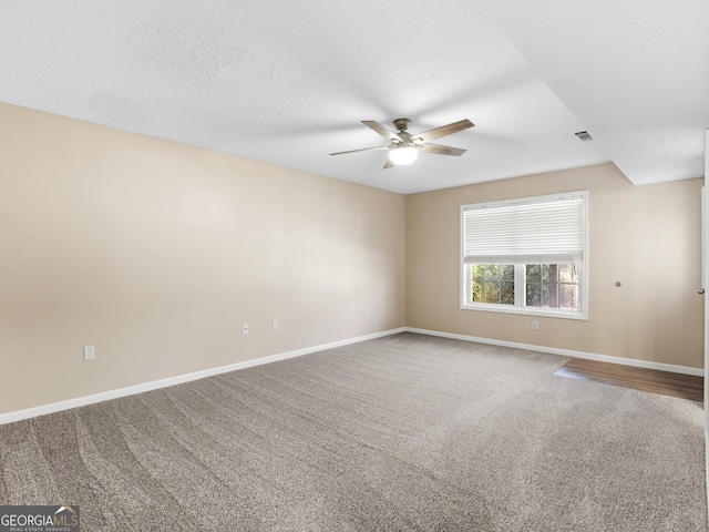 spare room with a textured ceiling, ceiling fan, visible vents, baseboards, and carpet