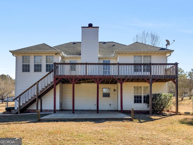 back of property with a deck, a patio, a yard, and a chimney