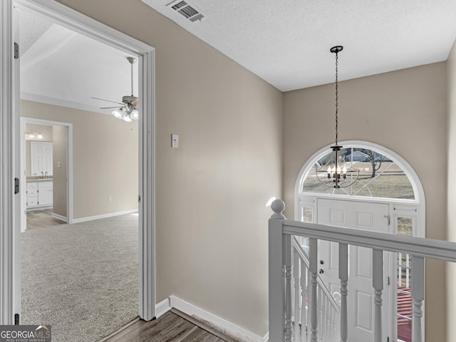 corridor with baseboards, an upstairs landing, visible vents, and a notable chandelier