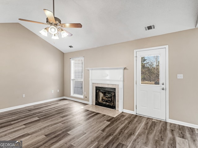 unfurnished living room featuring a wealth of natural light, vaulted ceiling, and wood finished floors