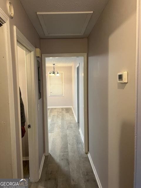 corridor featuring dark wood-type flooring, attic access, and baseboards