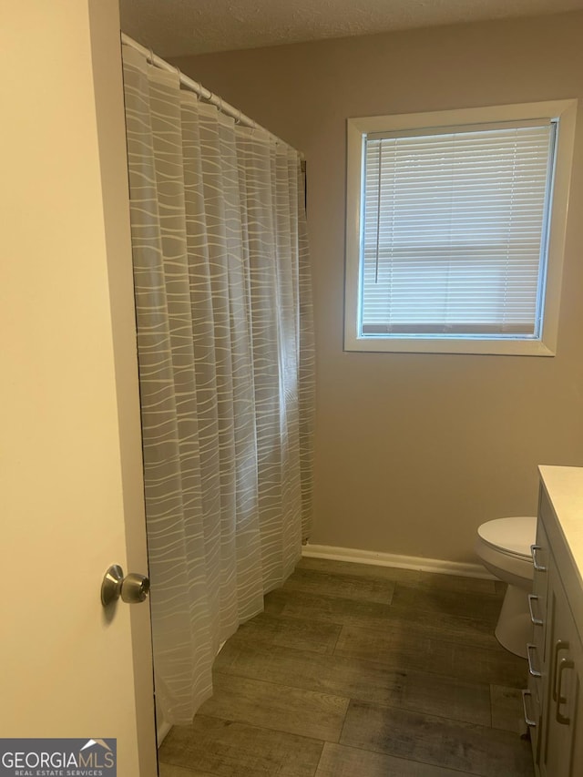 bathroom featuring toilet, baseboards, a shower with shower curtain, and vanity