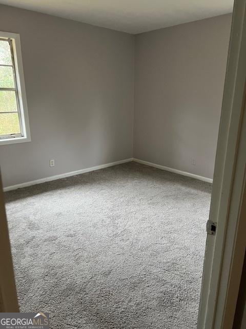 carpeted spare room featuring baseboards