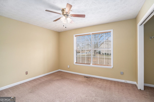 empty room with carpet, visible vents, baseboards, a textured ceiling, and ceiling fan