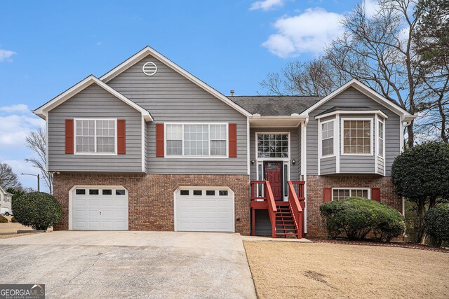 bi-level home featuring concrete driveway, brick siding, roof with shingles, and a garage