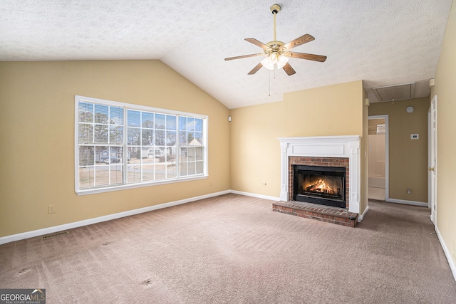 unfurnished living room with attic access, ceiling fan, carpet floors, a fireplace, and visible vents