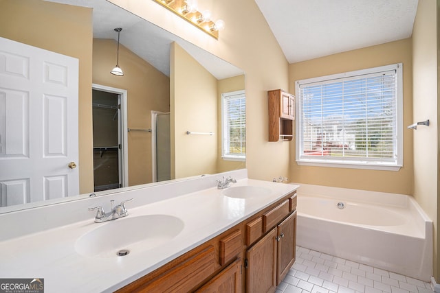 full bath featuring a garden tub, tile patterned floors, vaulted ceiling, and a sink