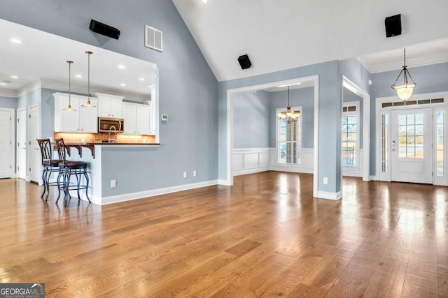 unfurnished living room featuring visible vents, high vaulted ceiling, wood finished floors, and a wealth of natural light