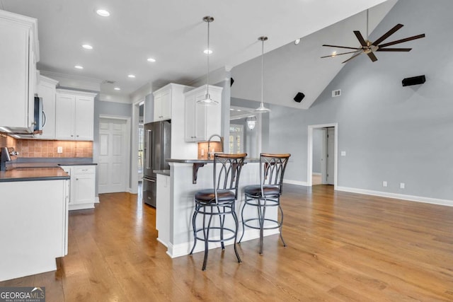 kitchen featuring stainless steel appliances, a breakfast bar, a peninsula, and white cabinets