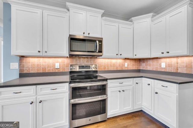 kitchen featuring appliances with stainless steel finishes, dark countertops, white cabinetry, and decorative backsplash