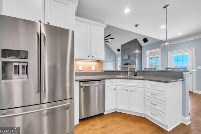 kitchen featuring dark countertops, a peninsula, stainless steel appliances, and a sink