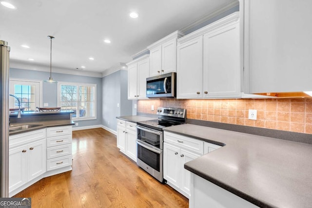 kitchen featuring stainless steel appliances, dark countertops, white cabinetry, and tasteful backsplash