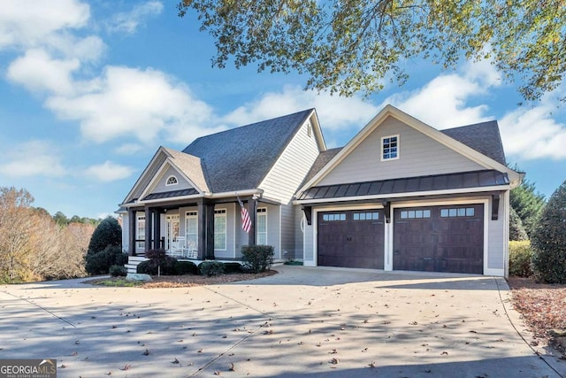 view of front facade with a porch, an attached garage, a standing seam roof, metal roof, and driveway