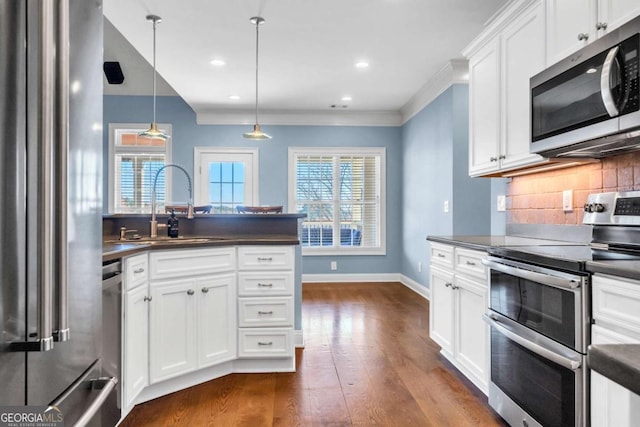 kitchen featuring appliances with stainless steel finishes, backsplash, dark countertops, and a sink