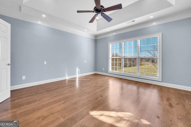 spare room with a tray ceiling, recessed lighting, wood finished floors, and baseboards