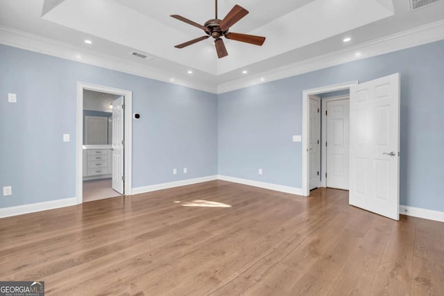 unfurnished bedroom with recessed lighting, wood finished floors, baseboards, a raised ceiling, and crown molding