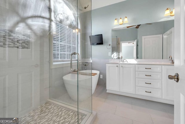 bathroom featuring double vanity, a stall shower, tile patterned floors, a freestanding tub, and tile walls