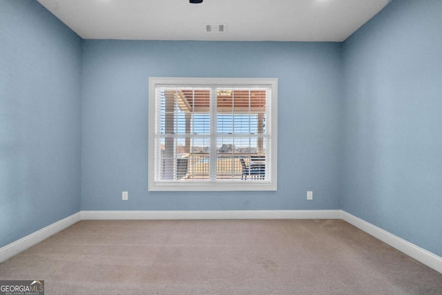 empty room with baseboards, visible vents, and carpet flooring