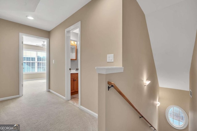 corridor featuring recessed lighting, light colored carpet, a sink, an upstairs landing, and baseboards