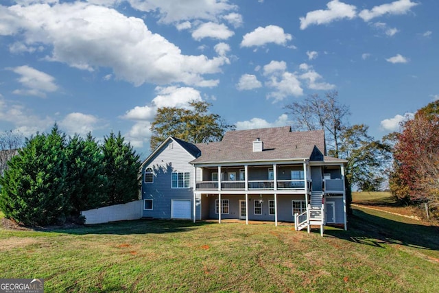 rear view of house with a chimney, an attached garage, a yard, stairs, and a wooden deck