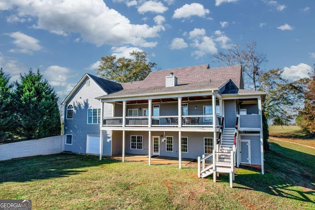 back of property with a garage, a lawn, a patio, a chimney, and stairs