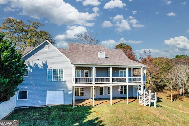 rear view of property featuring a garage, driveway, stairway, a lawn, and a chimney